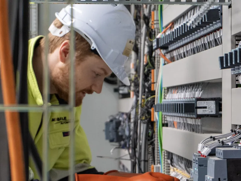Electrician terminating control cabinet wiring during a steel plant installation